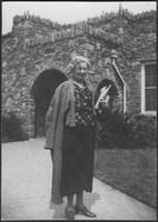 M. Bessie DeGraw in front of a building at Madison College, holding books