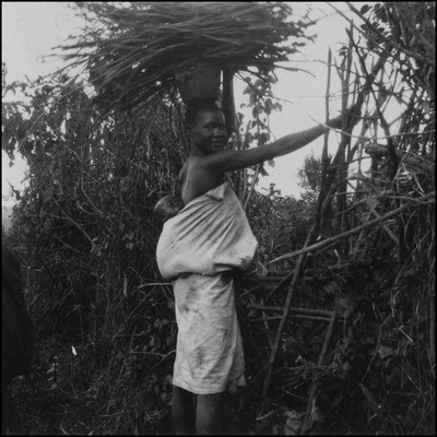 Kisii woman with baby and a load of wood on her head