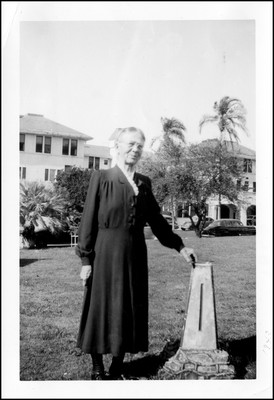 Ida Gates posing beside a marker, possibly in Singapore