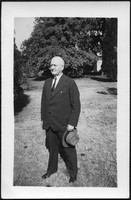 Edward A. Sutherland standing on lawn with hat in hand