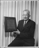 Dr. Joseph E. Sutherland holds a plaque called "The Oath of Hippocrates"