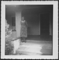 Bessie DeGraw standing on the porch of a house in the summer of 1957